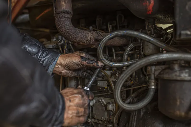 A diesel mechanic's grease-stained hands working on a Bledsoe truck engine — heavy-duty diesel repair in Oklahoma City performed by certified technicians.