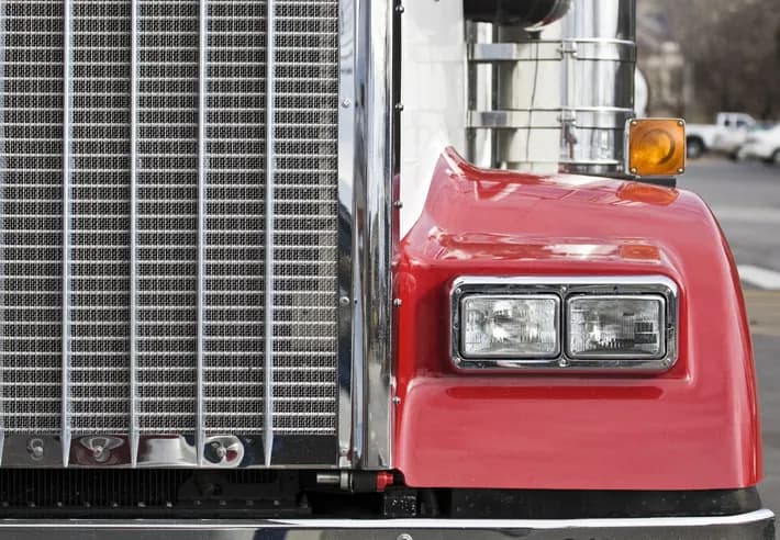Heavy-duty truck radiator, chrome grille, and headlight detail — Bledsoe's Oklahoma City shop repairs cooling systems, charging systems, and front-end electrical for semi trucks.